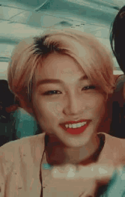 a close up of a person with blonde hair and red lipstick smiling .