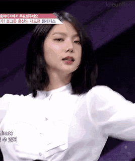 a woman in a white shirt is standing in front of a purple wall .