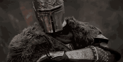 a close up of a knight wearing armor and a helmet with a fur coat .