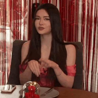 a woman is sitting at a table with a plate of food and a phone .