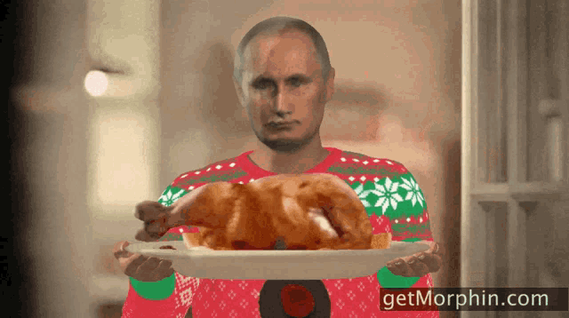 a man in a red and green sweater holds a turkey on a plate