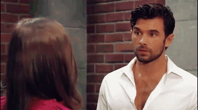 a man in a white shirt looks at a woman in a pink shirt