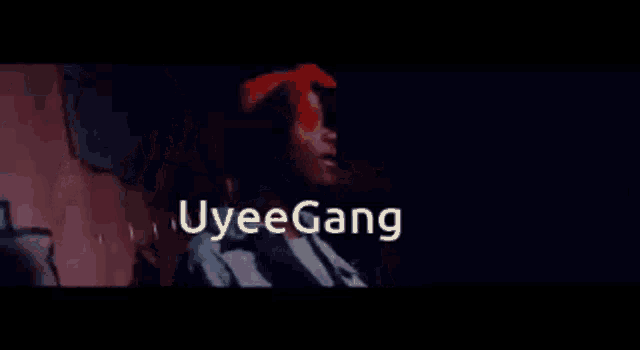 a man in a red bandana is smoking a cigarette in a dark room with the words uyeegang above him