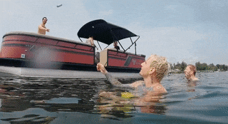 a man in a yellow swimsuit is swimming in the water near a boat