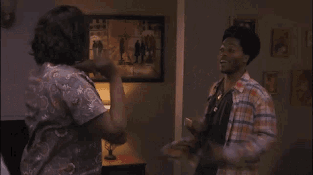 a man and a woman are dancing in a living room in front of a picture .