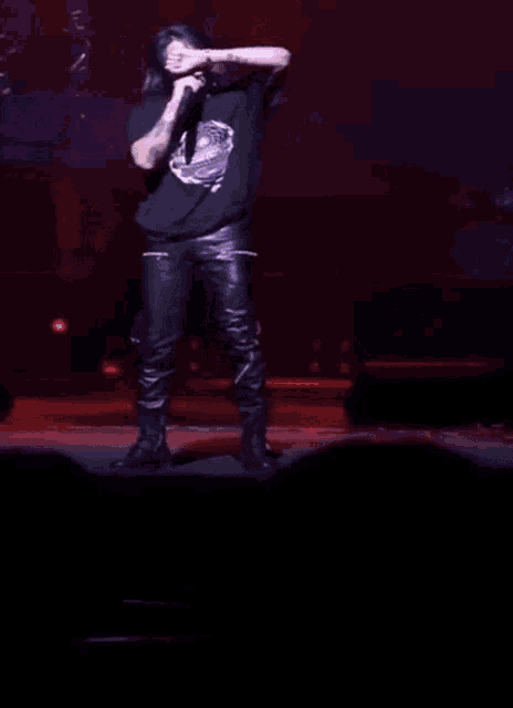 a man singing into a microphone on a stage with a large screen behind him