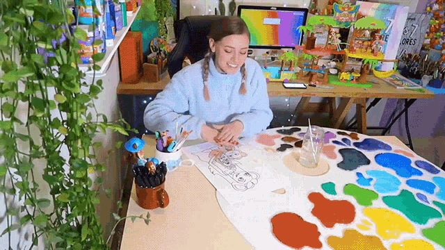 a woman is sitting at a table painting a picture of a dog
