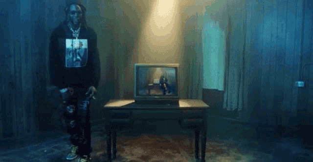 a man is standing in a dark room next to a television .