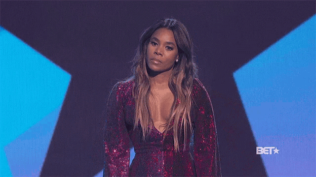 a woman in a red sequined dress is standing in front of a blue background .