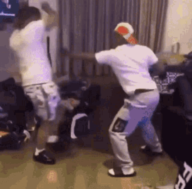 two men are dancing in a living room with a couch in the background .