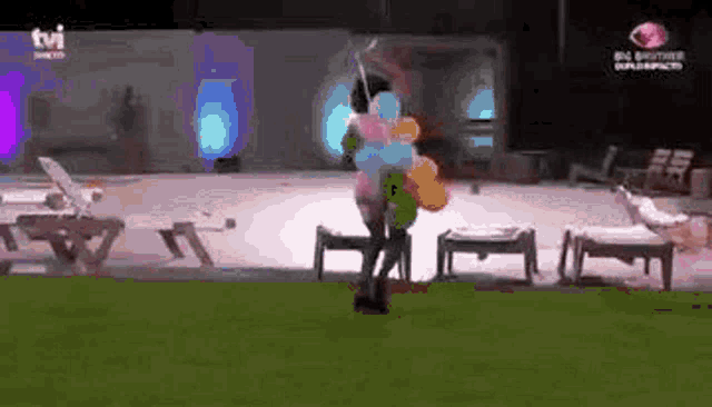 a woman is holding a bunch of balloons in her arms while standing in the grass .