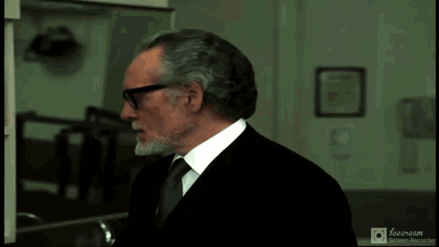 a man with glasses and a beard says " merci "