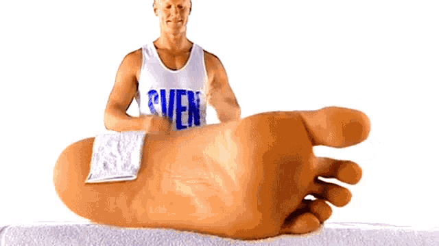 a man standing next to a large foot with a towel on it and a shirt that says ' r ' on it