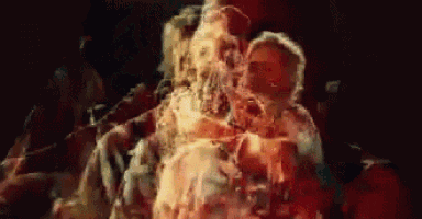 a blurry picture of a group of people dancing in a dark room with a red light behind them