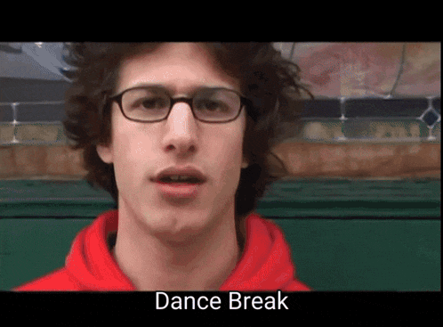 a young man wearing glasses and a red hoodie says " dance break "
