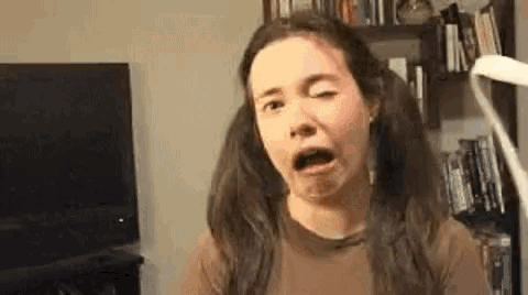a woman with pigtails is making a funny face while sitting in front of a television .