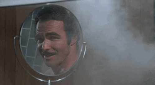 a man with a mustache is looking in a mirror