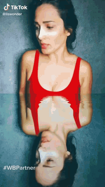 a woman in a red tank top is reflected in another woman 's face