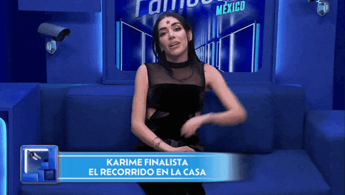 a woman is sitting on a blue couch with a banner that says karime finalista el recorrido en la casa