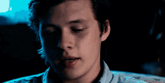 a close up of a young man 's face with his eyes closed in a dark room .
