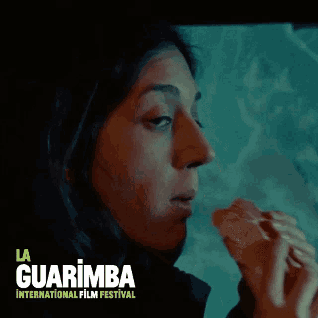 a woman is eating a sandwich with la guarimba international film festival written on the bottom