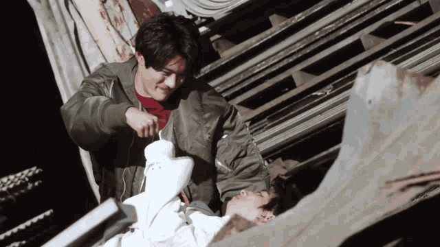 a man in a green jacket is putting something on another man 's shirt