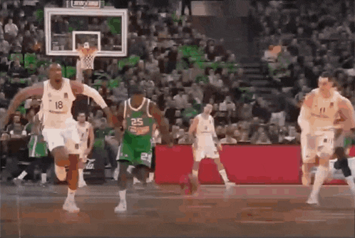 a group of basketball players are playing a game of basketball on a court in front of a crowd .