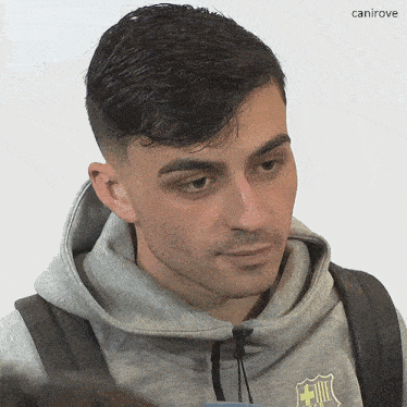 a close up of a man wearing a grey hoodie with a fcb logo on it
