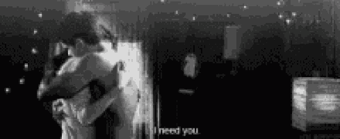 a black and white photo of a man and woman hugging each other in a room .