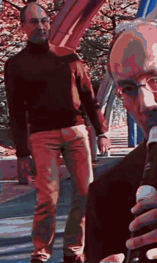 a man wearing a black turtleneck stands next to another man