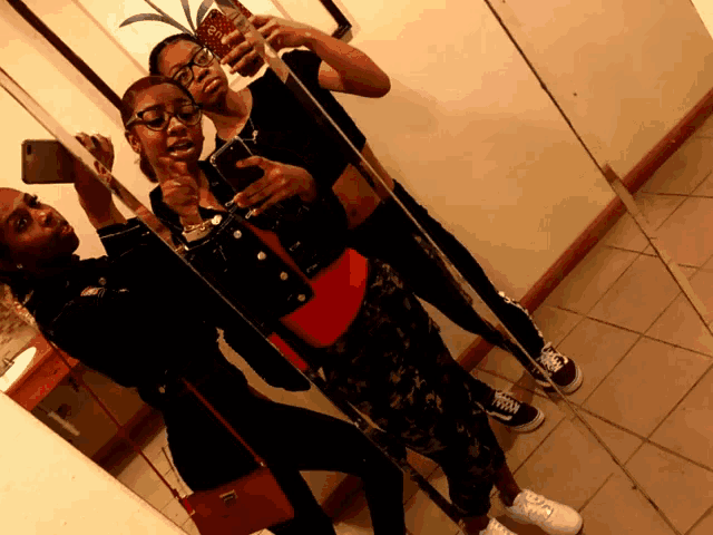 three girls are taking a selfie in front of a mirror and one of them has a pineapple on her phone