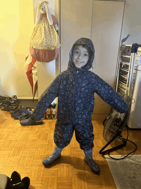 a young boy wearing a hooded jacket and rain boots