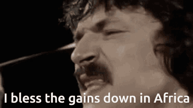 a man with a mustache singing into a microphone with the words i bless the gains down in africa
