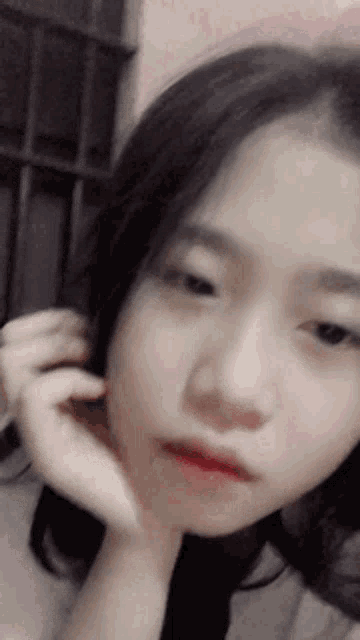 a close up of a young girl 's face with her hand on her chin