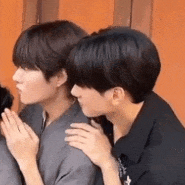 a couple of young men are sitting next to each other and one of them is touching the other 's shoulder .