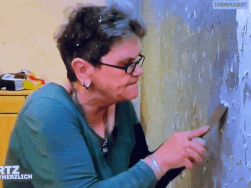 a woman wearing glasses is working on a wall with the words rtl herzlich on the bottom right