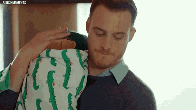 a man and a woman are holding a baby in a blanket with crocodiles on it .