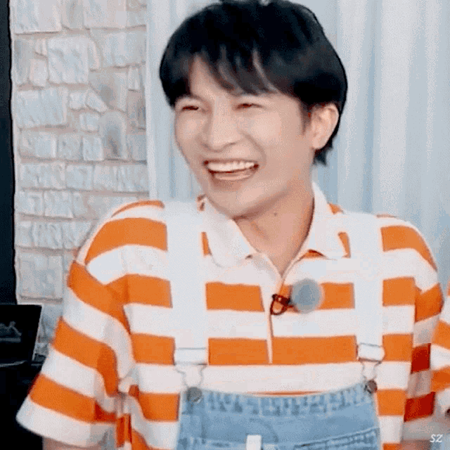 a man wearing a striped shirt and overalls is smiling .