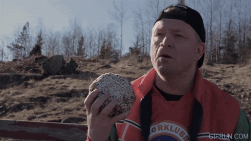 a man wearing a shirt that says orklubb is holding a donut in his hand