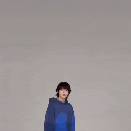 a man in a blue sweater is dancing in front of a white background .