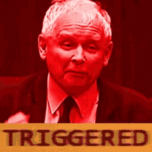 a man in a suit and tie is holding a sign that says triggered in red .
