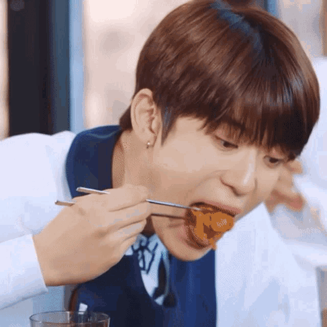 a man is eating a piece of food with chopsticks .