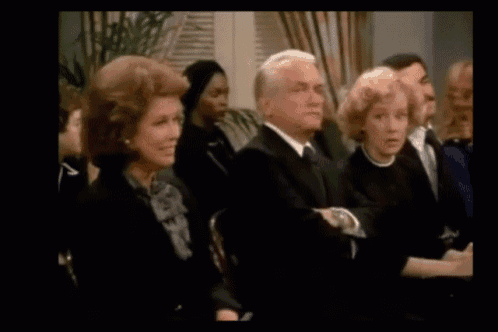 a group of people sitting in a room with a man in a suit