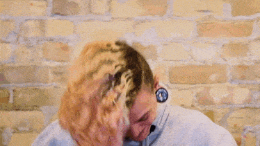 a man with a tattoo on his neck is wearing a grey hoodie and smiling .
