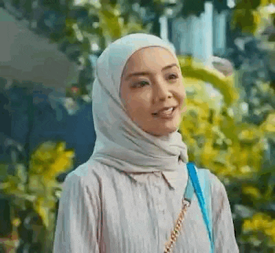 a woman wearing a hijab and a blue purse is smiling and looking at the camera .