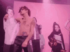 a group of people are dancing on a stage with a pink background .