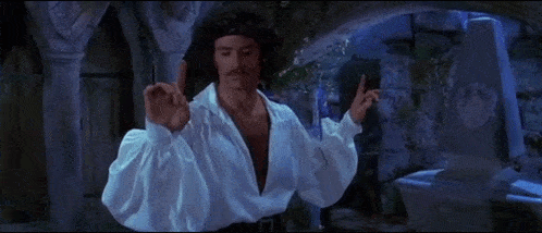 a man in a white shirt and black pants is standing in a dark room with his arms outstretched .