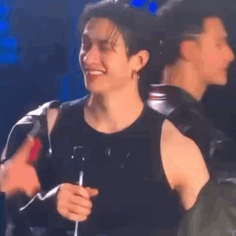 a man is smiling while holding a microphone on a stage .