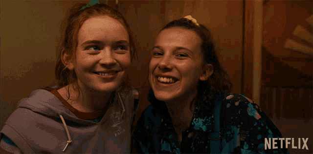 two girls are smiling in front of a netflix sign