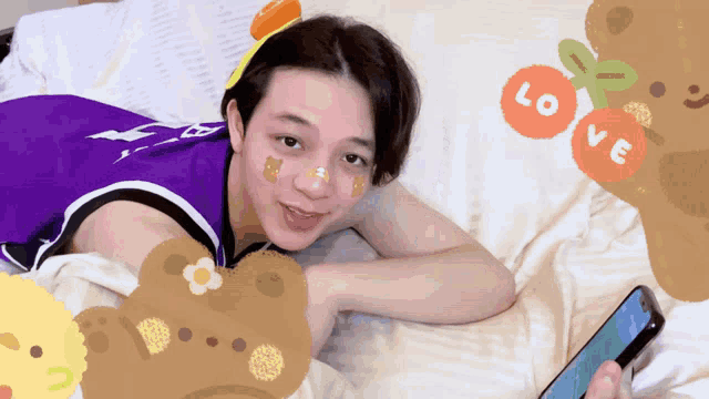 a person laying on a bed with stickers on their face including one that says love